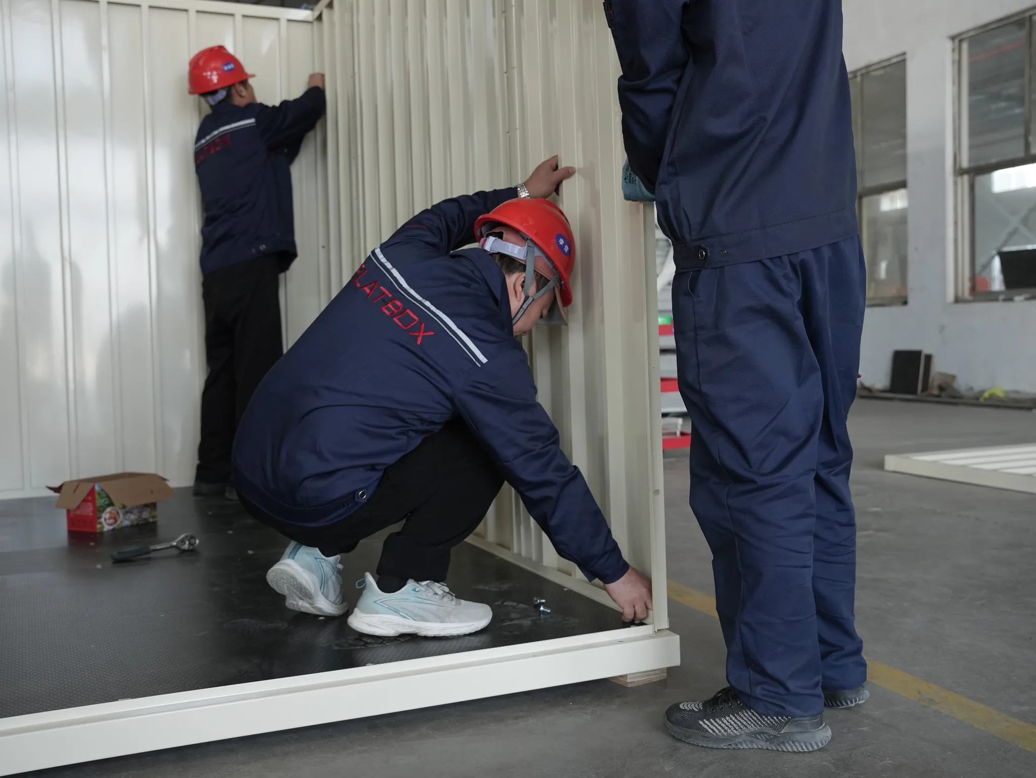 Flatbox team assembling a modular storage container inside a manufacturing facility