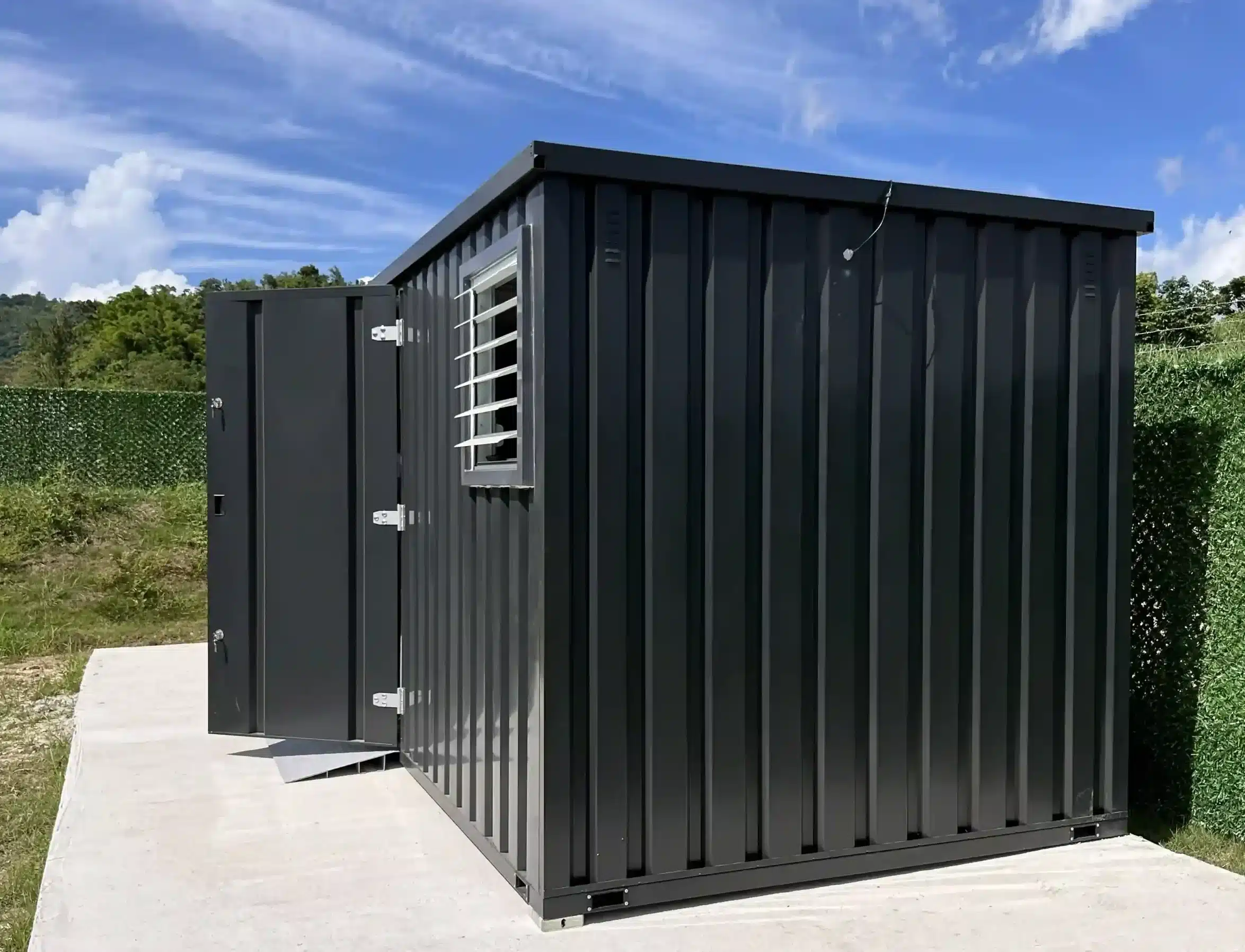 Black flat-pack site office container with open door on an outdoor property site